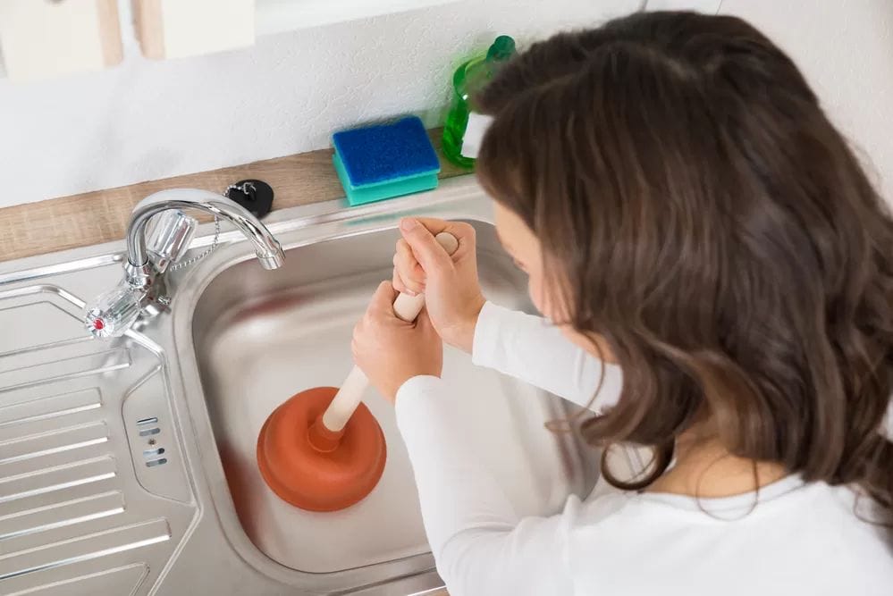 Woman Unclogging Drain Melbourne